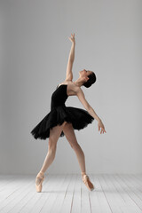 Young beautiful skinny ballerina is posing in studio