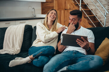 Wall Mural - Happy couple using a digital tablet at home