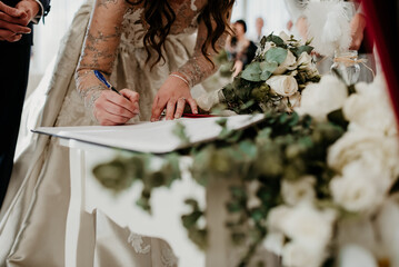 womans hands with gold and silver rings on fingers groom putting on ring on wedding day bride