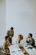 © BGStock72 - Group of young business people working and communicating while sitting at the office desk together