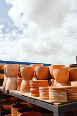 Wall Mural - Stacked clay pots at sale in a garden center with blue sky in the background during spring