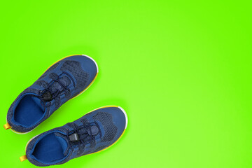 New blue children sneakers on green background with copy space.