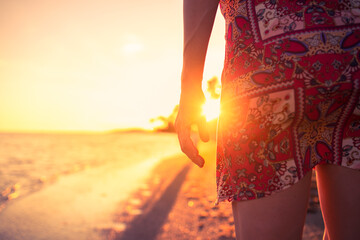 silhouette of a person walking on the beach facing the sunlight