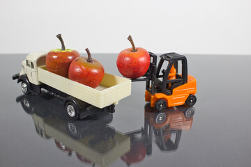 Closeup of a miniature figure of a worker in a forklift unloading the apples in a truck