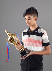 Indian school boy holding a golden trophy cup	
