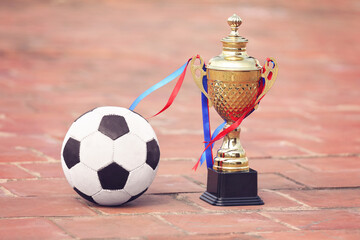 Gold winners trophy or champion cup with Football on floor 