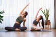 © chayantorn - Asian young mother and her daughter setting prepare to yoga and meditation pose together on yoga mat in living room at home.