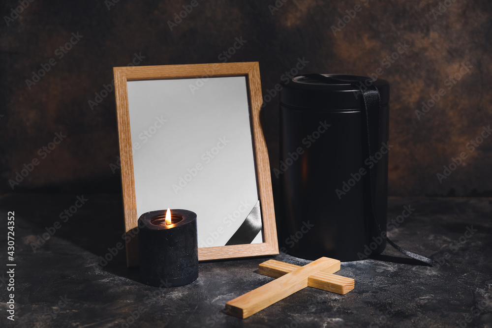 Blank photo frame and urn on dark background