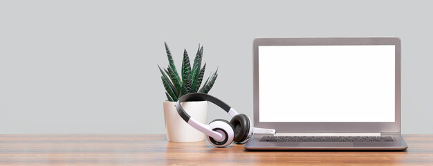 Wall Mural - Laptop. Mockup screen and headphones on wooden desk and plain background banner. Distant learning. working from home, online courses or support minimal concept. Helpdesk or call center headset