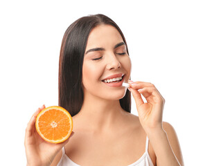 Wall Mural - Beautiful woman with orange taking vitamin C pill on white background