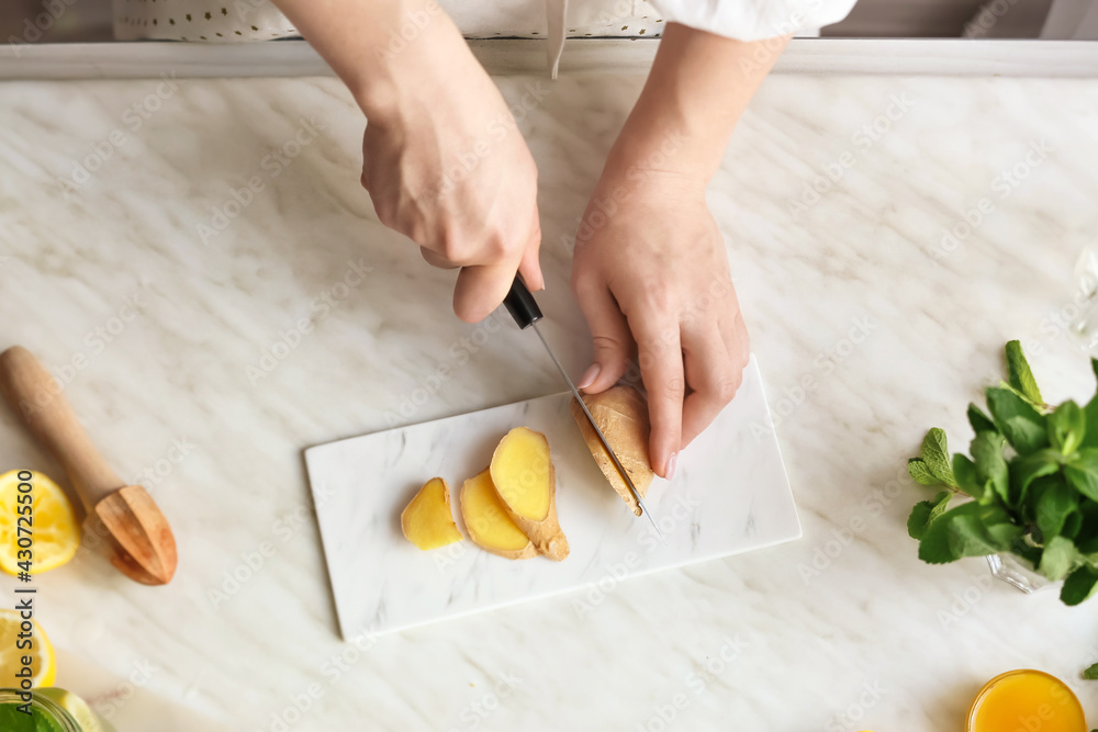 Woman preparing ginger lemonade in kitchen