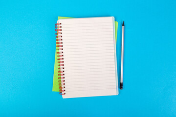 Wall Mural - school notebooks on a blue background, spiral notepad with a blank page and a pencil on the table top view