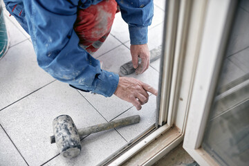 Wall Mural - Professional ceramics tile man worker placing new tiles on the floor and wall.