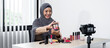 © Ngampol - Asian muslim woman beauty blogger looking at the camera to review eye shadow showing on her hand