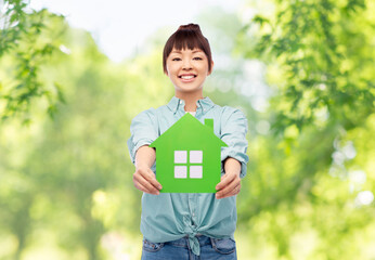 Wall Mural - eco living, environment and sustainability concept - portrait of happy smiling young asian woman in turquoise shirt holding green house over natural background