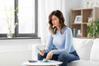 © Syda Productions - business, finances, income and people concept - woman with calculator and bills counting money at home