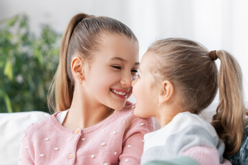 Wall Mural - family, childhood and friendship concept - two happy smiling little girls or sisters at home