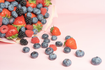 Wall Mural - Edible bouquet of fresh berries, blueberries, raspberries, strawberries, hedgehog on a pink background with scattered berries. View from the top .Close-up .Concept of a useful gift, 