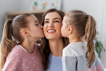 Wall Mural - people, family and love concept - two daughters kissing happy mother at home