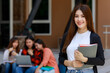 © Bangkok Click Studio - Young and beautiful Asian college student girls holding books, pose to camera with group of friends blur in background against school building. Learning and friendship of teens close friend concept