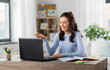 © Syda Productions - distant education, remote job and people concept - happy smiling female teacher with laptop computer having online class or video call at home office