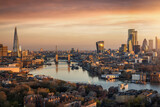 Fototapeta Londyn - Panoramic, aerial view to the urban skyline of London during a golden sunrise with Tower Bridge and the skyscrapers of the City district, United Kingdom