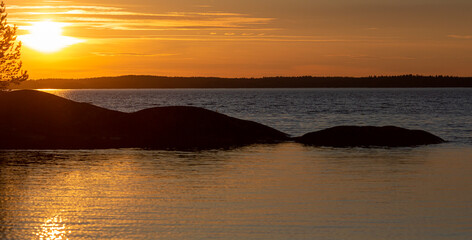 Wall Mural - Colorful and calm sunset landscape in Finland. Glowing sky with silhouette trees.