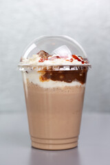 sweet milkshake in a plastic glass on a gray background