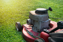 Mowing A Lawn With A Old Style Petrol Gasoline Lawnmower. Red Lawn Mower Cutting Grass . Gardening Concept Background