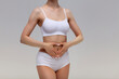 Slim woman in white underwear forming a heart symbol with her hands on her belly