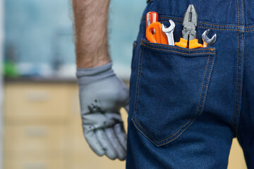 Close up shot of various plumbing hand tools in man's jeans back pocket