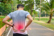 © เลิศลักษณ์ ทิพชัย - Young Asian men exercising in the park Pain in the back and using a hand to hold on my back That hurts while experiencing severe pain: exercise injury concepts