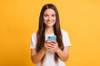 © deagreez - Photo portrait of female blogger browsing internet keeping mobile phone smiling isolated on bright yellow color background