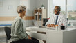 © Gorodenkoff - African American Family Doctor is Prescribing Medication to Senior Female Patient and Speaking with Her During Consultation in a Health Clinic. Physician Sitting Behind a Desk in Hospital Office.