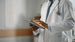 © Gorodenkoff - Close Up Shot of a African American Male Doctor Wearing White Coat Working on Tablet Computer at His Office. Medical Health Care Professional Working with Test Results, Patient Treatment Planning.