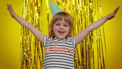 Excited cute little blonde teen kid child girl winning prize, celebrate birthday, scream rejoices doing winner success hands gesture say Yes. Young children posing isolated on yellow studio background