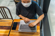 © Quang - High angle view photo of woman wearing protective mask and using laptop