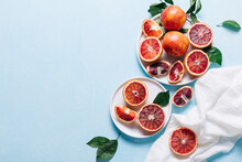 Composition Of Whole And Sliced Blood Oranges In A Plate On Light Blue Table Background. Flat Lay, Top View, Copy Space.