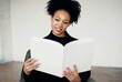 © muse studio - Reading holding a book textbook white cover blank. The student is a smart African American looking woman. Is in the Institute in the classroom in the classroom.
