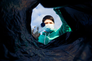 a woman throws a plastic bottle into a bag under the garbage, close-up, the concept of ecology and protection of the earth