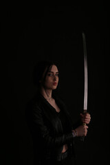 Woman with a katana sword on black background