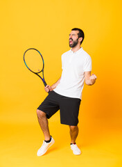 Full-length shot of man over isolated yellow background playing tennis and celebrating a victory