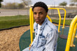 Portrait of a Young Male African American Teen Model Outdoors at the Park Sitting on a Carousel