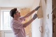 © RealPeopleStudio - Caucasian man tearing off old wallpaper from wall preparing for home redecoration