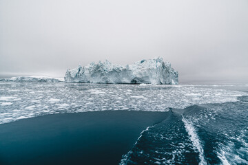 Arctic nature landscape with icebergs in Greenland icefjord with midnight sun sunset sunrise in the horizon. Early morning summer alpenglow during midnight season. Ilulissat, West Greenland.