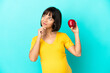 © luismolinero - Pregnant woman holding an apple isolated on blue background and looking up