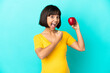 © luismolinero - Pregnant woman holding an apple isolated on blue background celebrating a victory