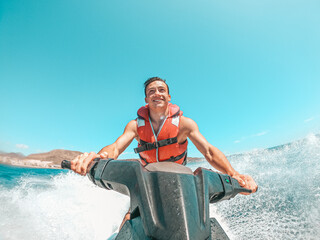 Teenager man enjoying summer in a jet ski in the middle of the sea having fun racing alone and isolated.