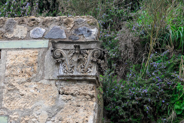 Close up detail of architectural column top set in stone wall in Pompeii, Italy 