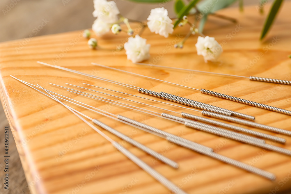 Stand with acupuncture needles and flowers, closeup